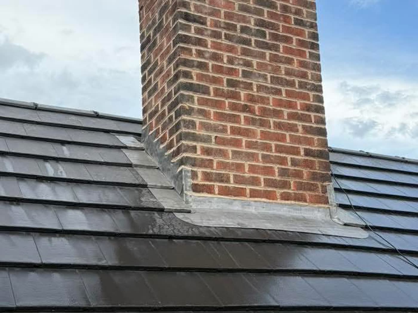 Brick chimney stack with new lead flashing dressed into the slate