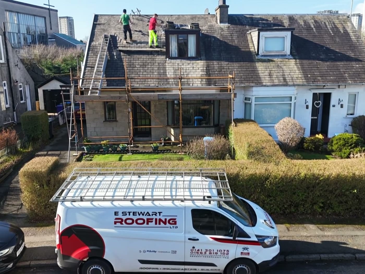 Drone view of a roof strip in progress with the E Stewart Roofing van on the street